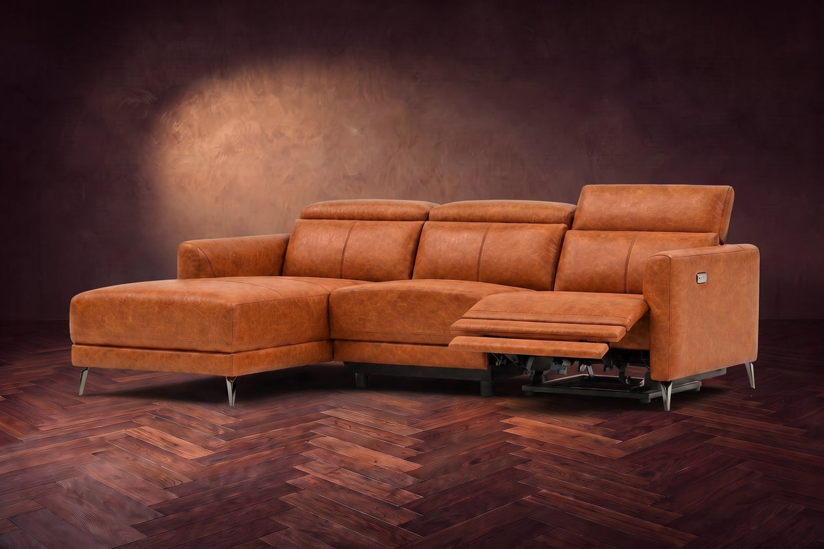 The Andria power reclining sectional on a walnut herringbone floor with the arm-end power recliner open: its two-tier footrest out and its headrest raised. Shown in Tuscan Cognac, Left chaise.