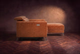 The Andria distressed leather sectional seen from its box-arm end, the chaise reaching forward, on a walnut herringbone floor. Shown in Tuscan Cognac, Right chaise.