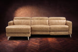 The Andria distressed leather reclining sectional seen from the front on a walnut herringbone floor, headrests down and the footrest closed. Shown in Washed Sand, Left chaise.