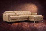 The Andria distressed Italian leather power reclining sectional on a walnut herringbone floor against a brown plaster wall, three-quarter view, headrests down and the footrest closed. Shown in Washed Sand, Right chaise.