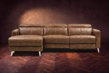 The Andria distressed leather reclining sectional seen from the front on a walnut herringbone floor, headrests down and the footrest closed. Shown in Weathered Saddle, Left chaise.