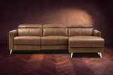 The Andria distressed leather reclining sectional seen from the front on a walnut herringbone floor, headrests down and the footrest closed. Shown in Weathered Saddle, Right chaise.