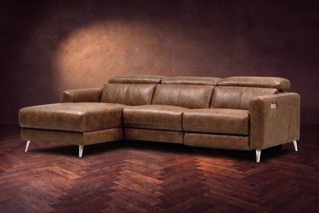 The Andria distressed Italian leather power reclining sectional on a walnut herringbone floor against a brown plaster wall, three-quarter view, headrests down and the footrest closed. Shown in Weathered Saddle, Left chaise.