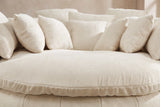 Close-up of the thick round seat cushion in beige basket-weave chenille, square pillows behind