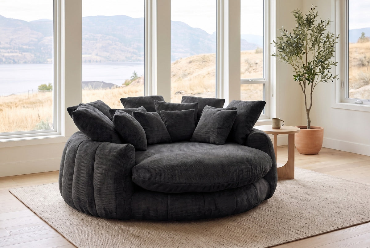 Aosta lounge chair in a Kelowna lake-house living room in the morning, the lake and dry hills beyond the windows (Black)
