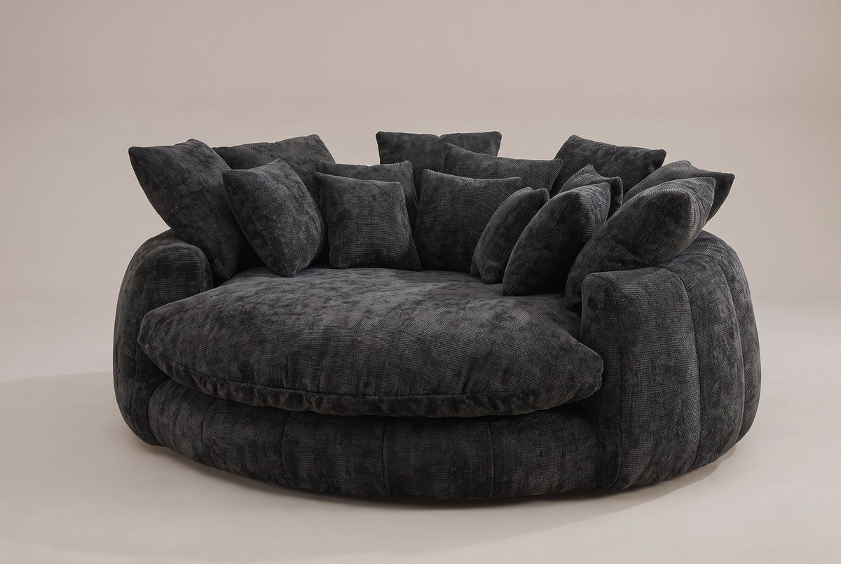 Aosta oversized round lounge chair in black chenille, three-quarter view on a warm grey studio backdrop