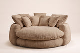 Aosta lounge chair in coffee, straight front view: one thick round seat cushion inside a low channelled ring, square pillows along the back