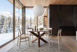 Apecchio round dining table in a Banff mountain house in winter, with a corten fireplace wall