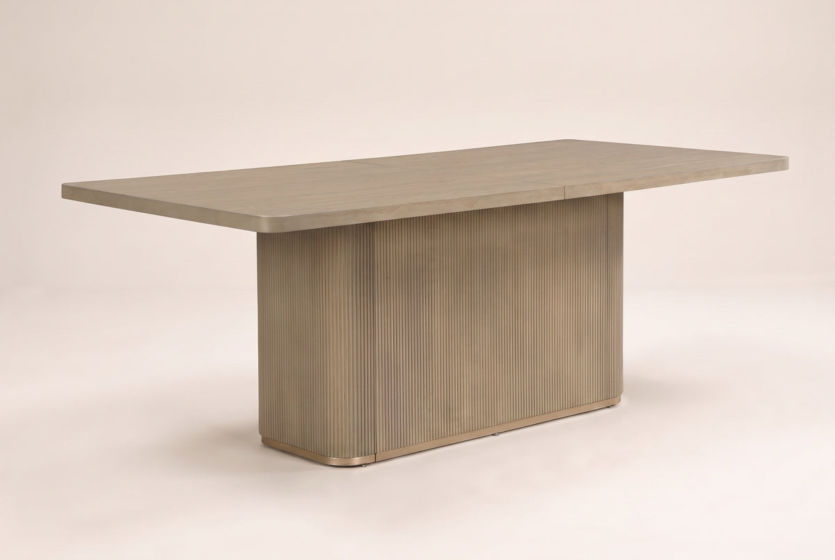 Aquileia 84-inch fluted pedestal dining table in Natural, three-quarter view on a warm off-white backdrop