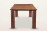 Arcevia dining table in Brown, end view on a warm white studio backdrop: round legs straight under the rounded corners