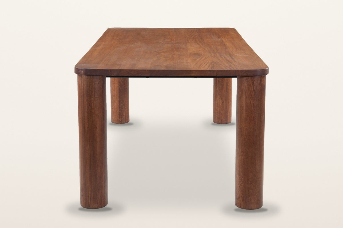 Arcevia dining table in Brown, end view on a warm white studio backdrop: round legs straight under the rounded corners