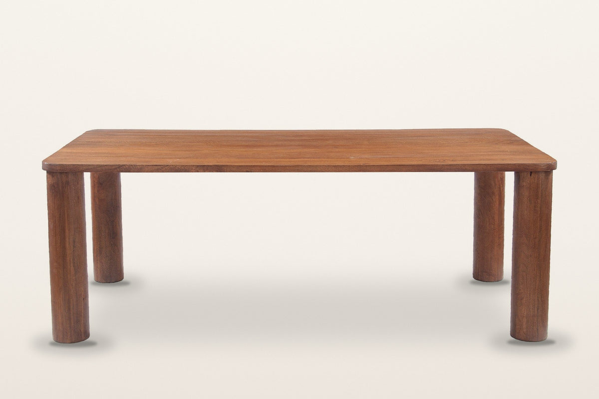 Arcevia dining table in Brown, straight front view on a warm white studio backdrop: a long slab top on four thick round legs