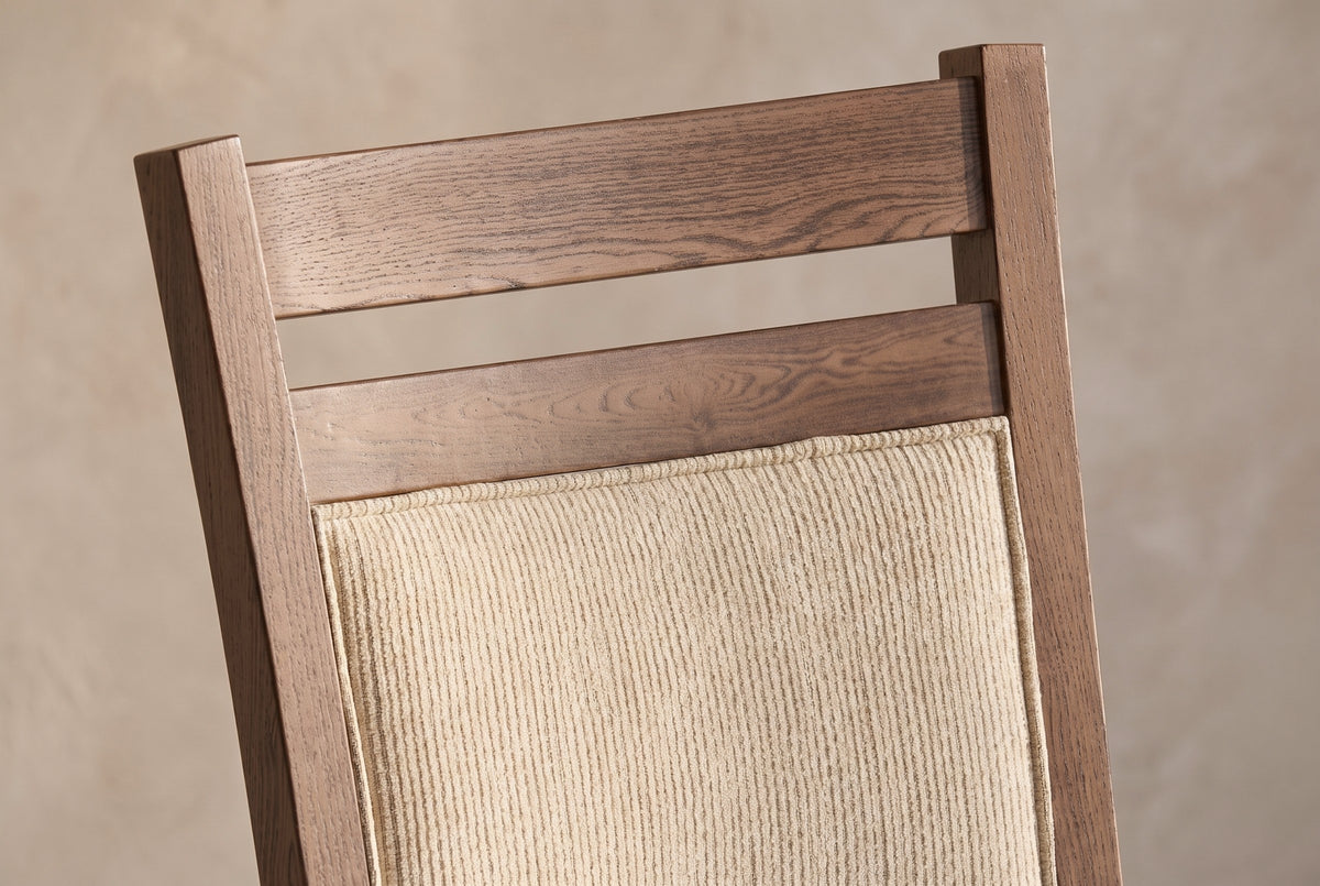 Close-up of the two walnut-finish rails and the top of the padded back panel of the Arden chair