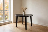 Arden drop-leaf dining table in Black with a jug of dried grasses, in the corner of a Plateau Mont-Royal apartment in Montreal, autumn maples beyond the balcony