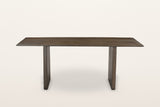 Arquata dining table in mocha seen along its long side: a thin top on two slab legs set in from the ends