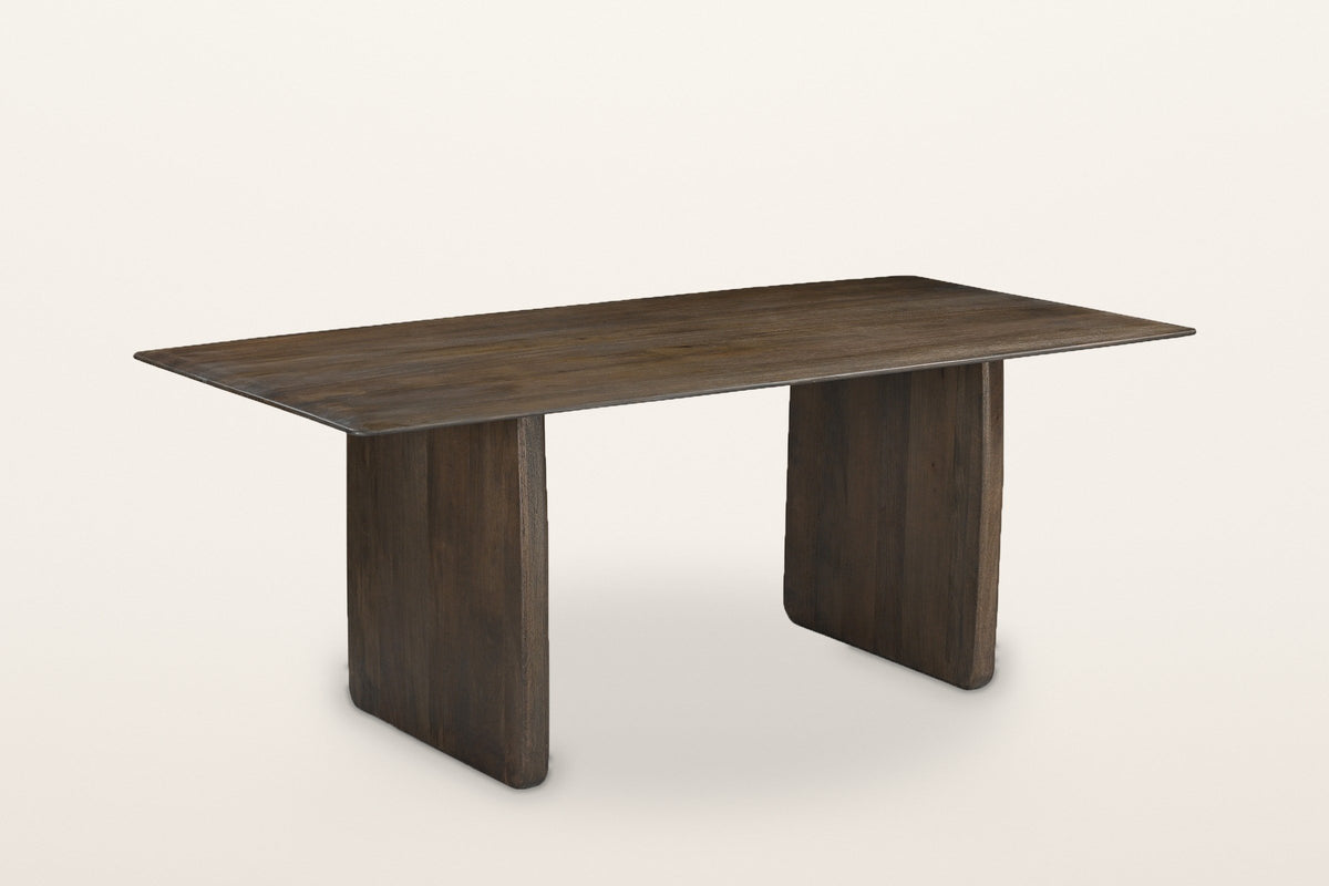 Arquata slab-leg dining table in mocha mango wood, three-quarter view on a warm white studio backdrop
