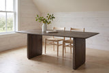 Arquata dining table in mocha mango wood in a Wolfville farmhouse dining room with whitewashed pine boards, an apple orchard through the window and apple branches in a white jug on top