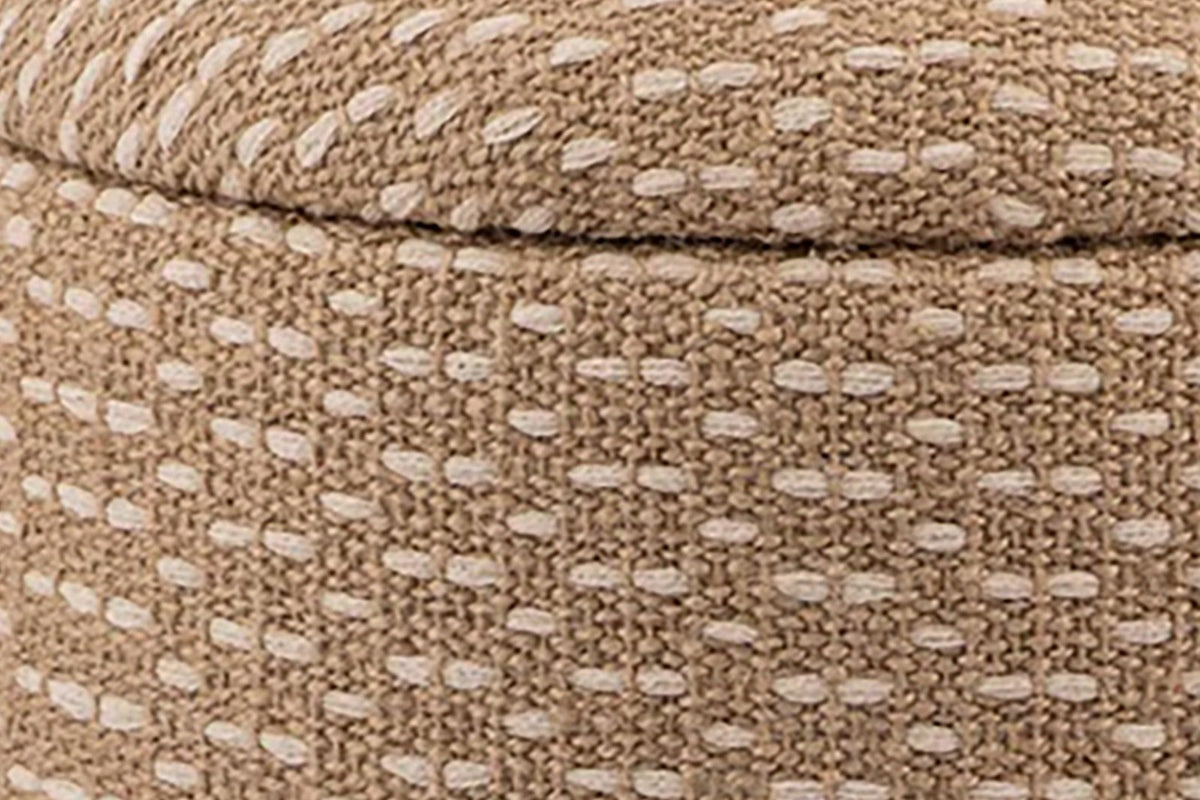 Close-up of the Arvier pouf in Camel: the padded lid's rounded edge sitting on the woven drum