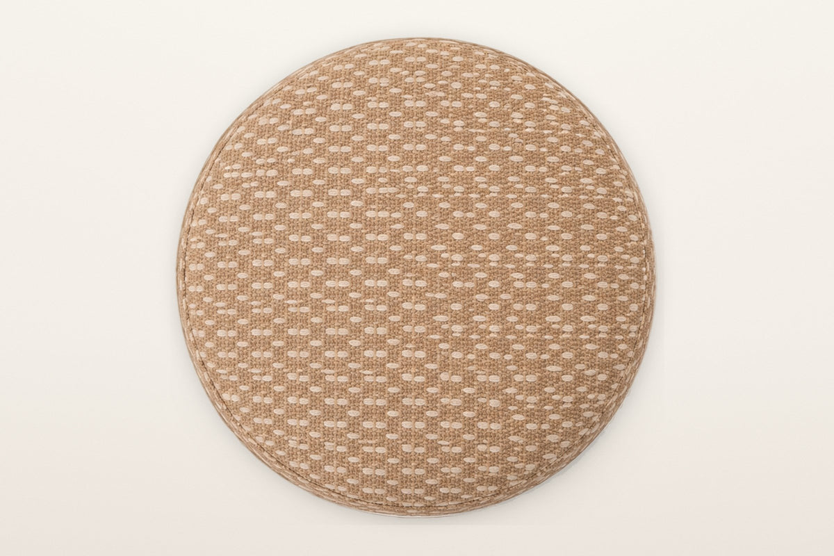 The Arvier pouf's padded round lid seen from above: camel jute with cream cotton dashes