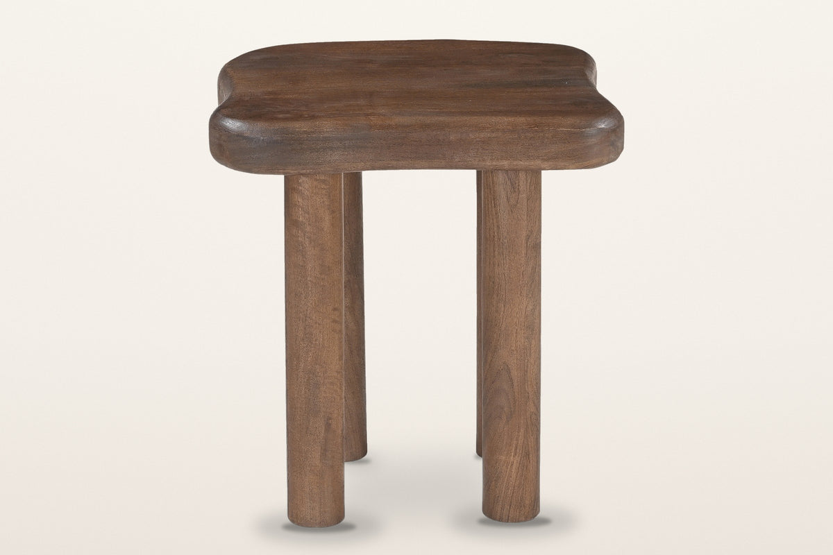 Atri side table in dark walnut, front view: a thick freeform top on four round post legs