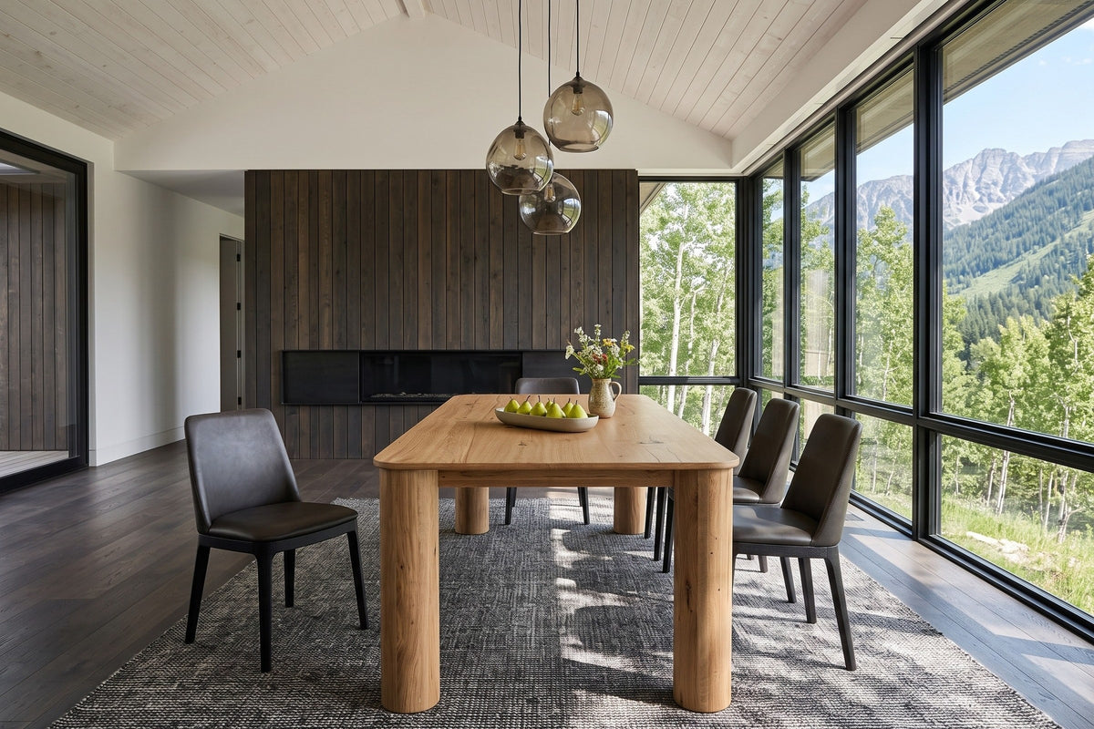 Atzara dining table seen from one end in a Fernie house in the BC Rockies, with a dark cedar fireplace wall