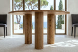 Close-up of the Atzara base at seat height: three plain round columns under the thin top, the sea through the glass behind