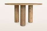 Atzara round dining table in Natural, level side view on a warm white studio backdrop: three column legs set well in under th