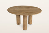 Atzara round oak dining table in Natural, three-quarter view on a warm white studio backdrop: a thin 55 in round top on three
