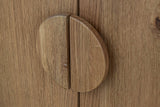 Close-up of the Atzara Small round pull in Natural, split in half where the two oak doors meet