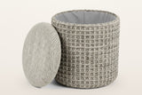 Balme pouf in Charcoal with the lid lifted off and leaning on the drum: storage inside, lined in light grey fabric