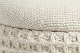 Close-up of the Balme pouf in Ivory: the domed lid's fine weave over the rolled rim and the square waffle knit