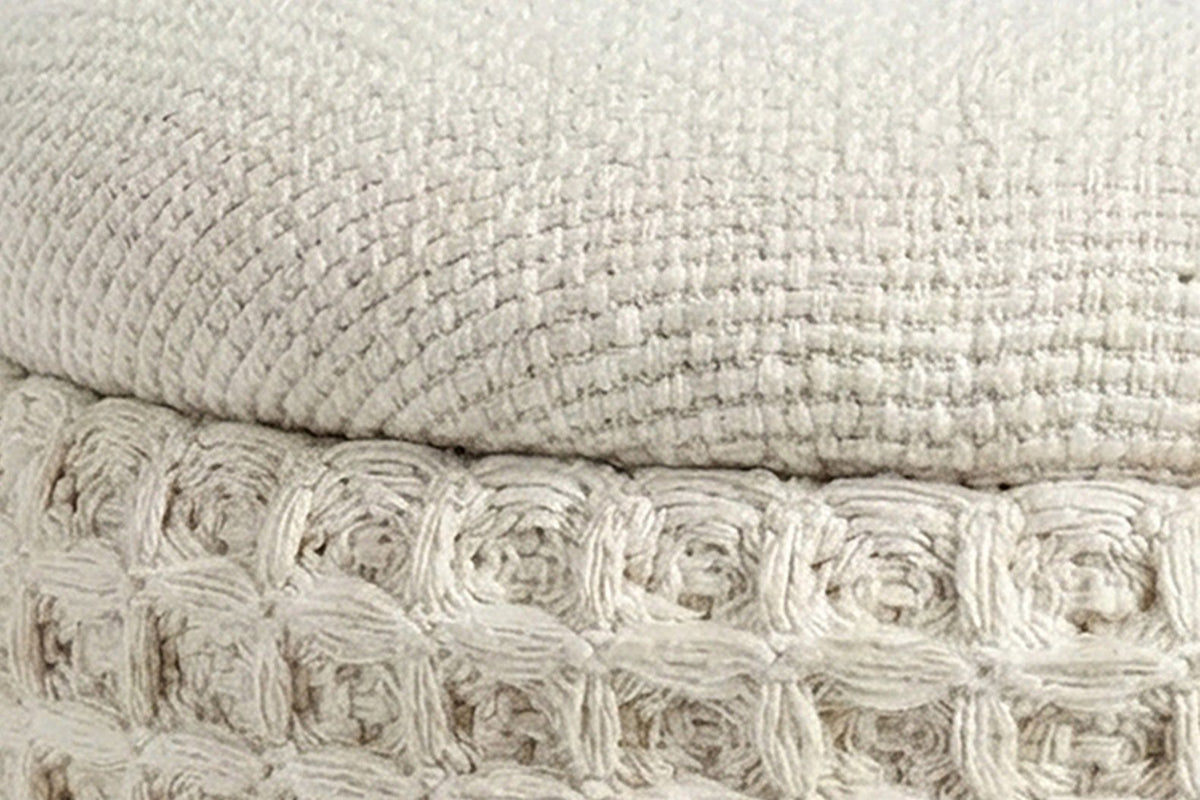 Close-up of the Balme pouf in Ivory: the domed lid's fine weave over the rolled rim and the square waffle knit