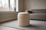 A Balme pouf in Ivory on a stone-grey wool rug in a brick house living room in the Glebe, Ottawa, a taupe-grey wool sofa behind and bare trees through the window