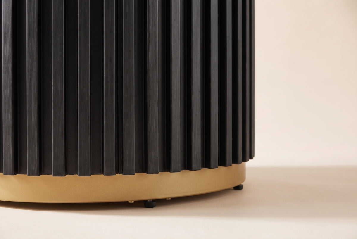 Close-up of the black fluted drum base: fine vertical slats stepping onto a gold-finished metal ring with small black feet