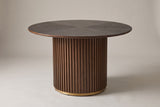 Bardolino round fluted pedestal dining table in walnut, three-quarter view on a warm grey studio backdrop