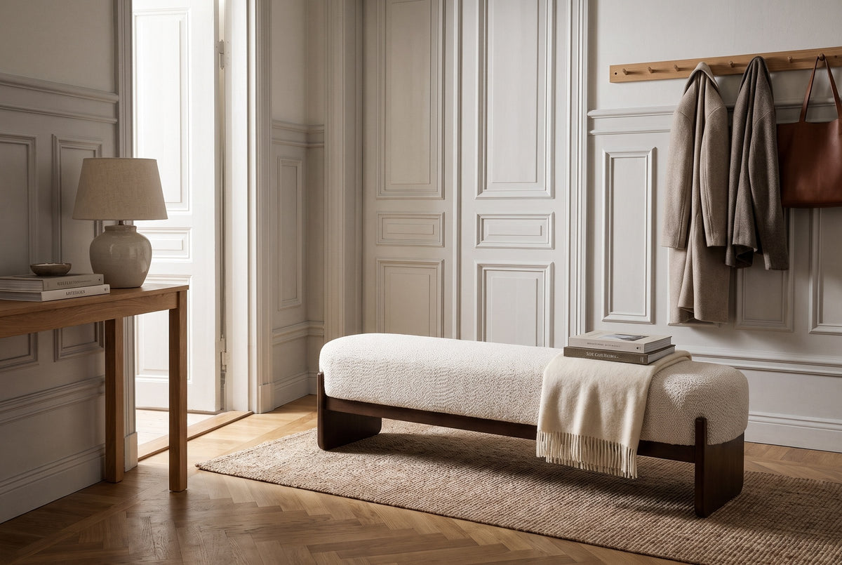 The Bassano bench in beige loop-yarn boucle on dark rubberwood slab legs along a panelled wall in a Stockholm apartment entrance hall, with a herringbone oak floor, an oak console and coats on a peg rail