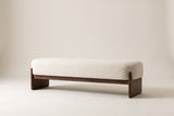 The Bassano bench in beige loop-yarn boucle on dark rubberwood slab legs, straight front view on an off-white studio background