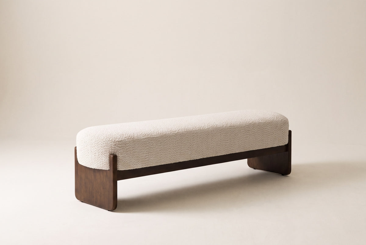 The Bassano bench in beige loop-yarn boucle on dark rubberwood slab legs, front three-quarter view on an off-white studio background