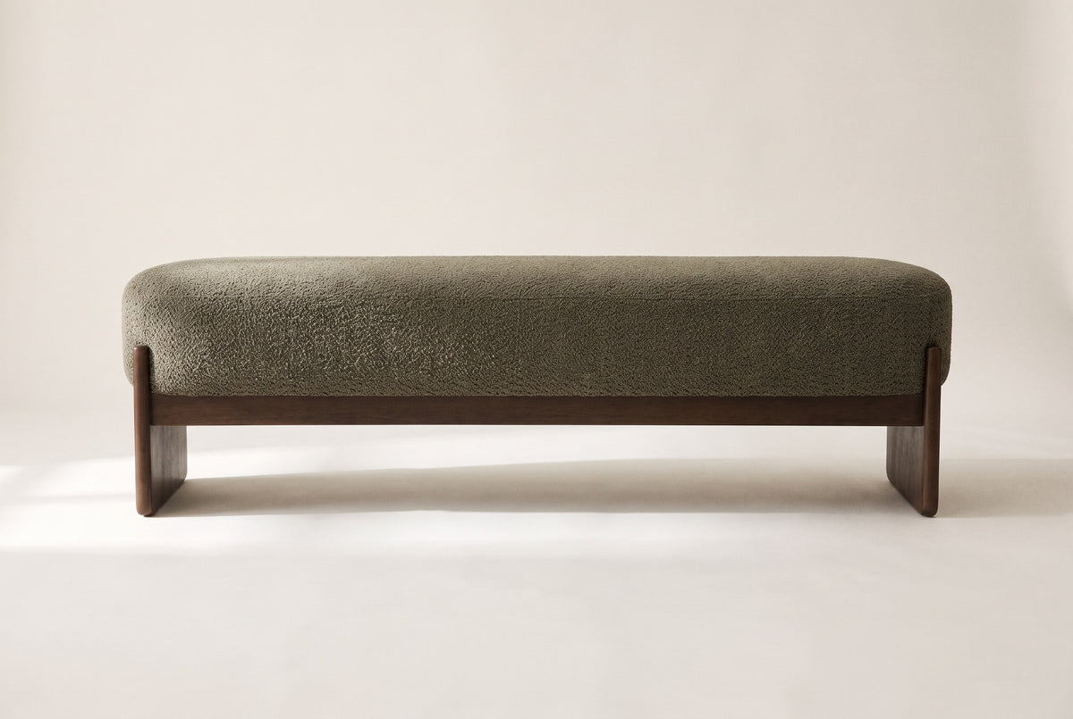 The Bassano bench in dark green loop-yarn boucle on dark rubberwood slab legs, straight front view on an off-white studio background