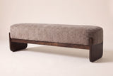Bassano bench in light brown loop-yarn boucle on dark rubberwood slab legs, three-quarter view on a warm cream studio backdrop