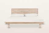 Bassiano bed in Light Driftwood, front view from the foot on a warm white studio backdrop: the wide rim over a recessed apron