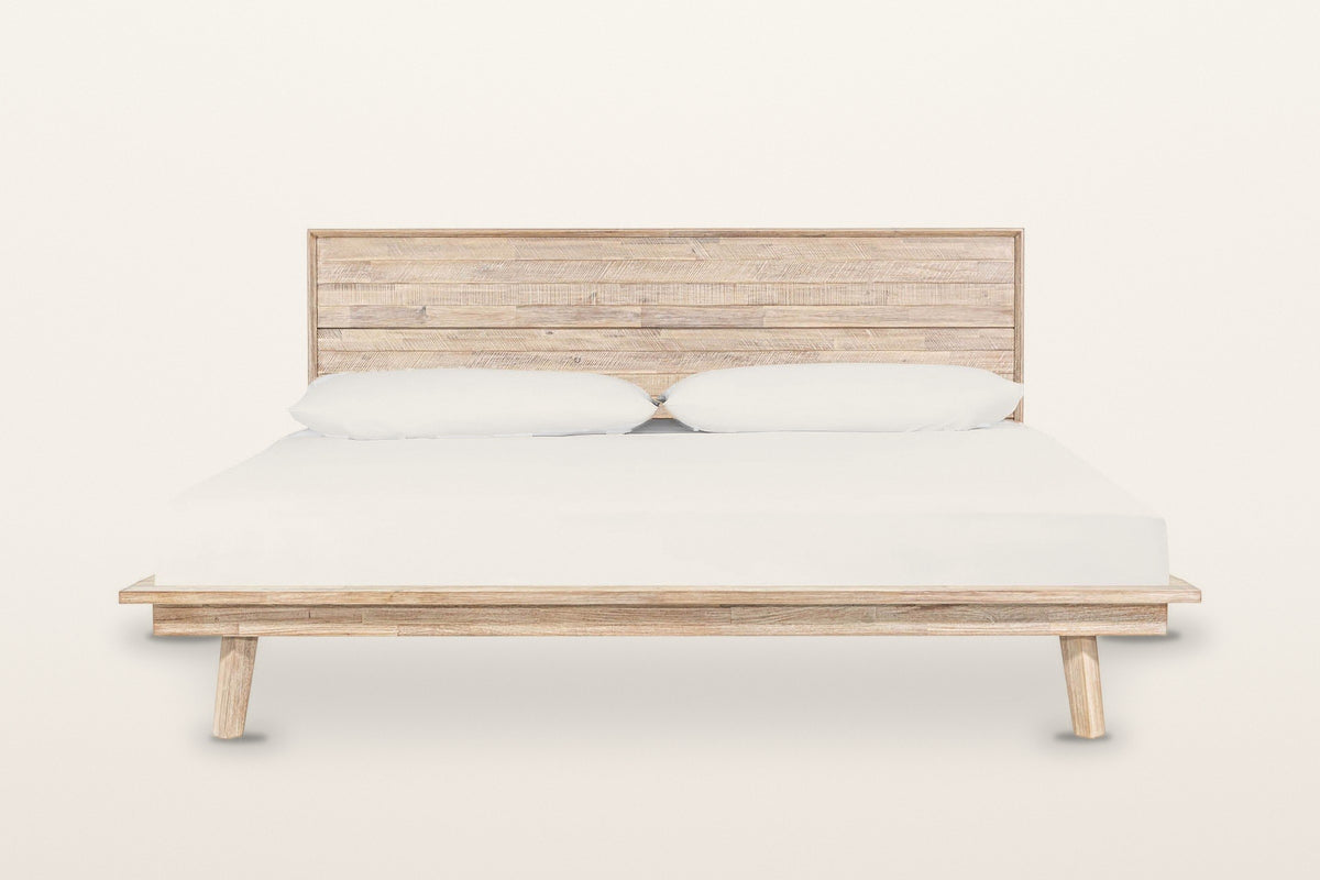Bassiano bed in Light Driftwood, front view from the foot on a warm white studio backdrop: the wide rim over a recessed apron