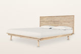 Bassiano bed in Light Driftwood acacia, three-quarter view on a warm white studio backdrop: a low platform with a wide rim
