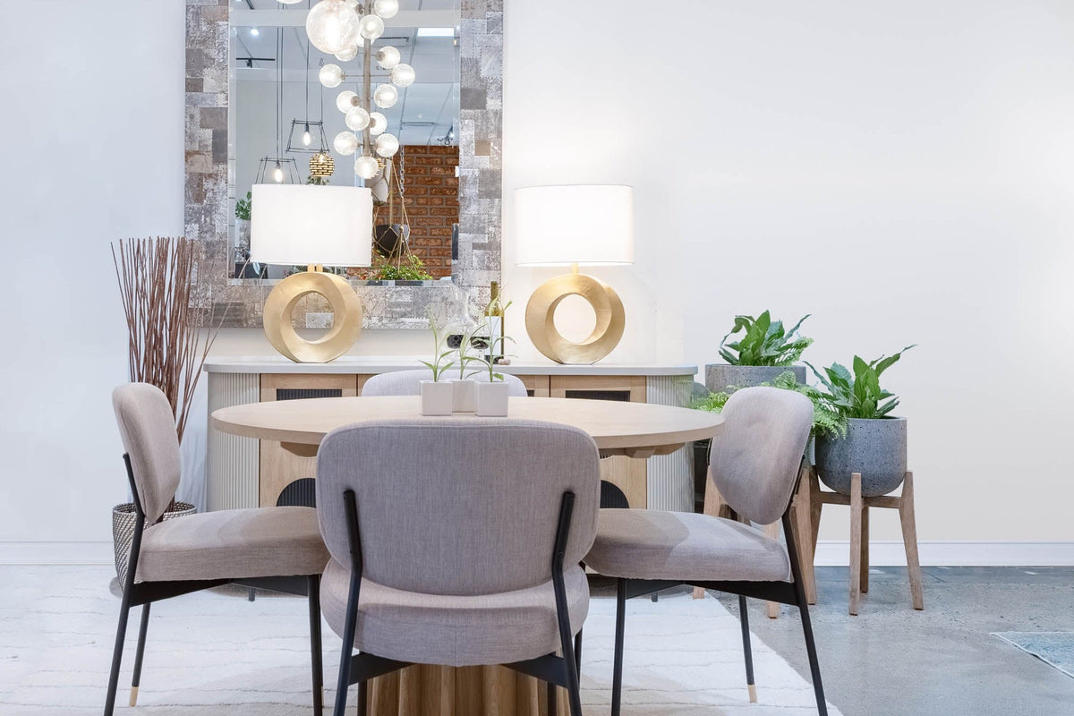 Pair of Bastien brass ring lamps on a sideboard behind a round dining table