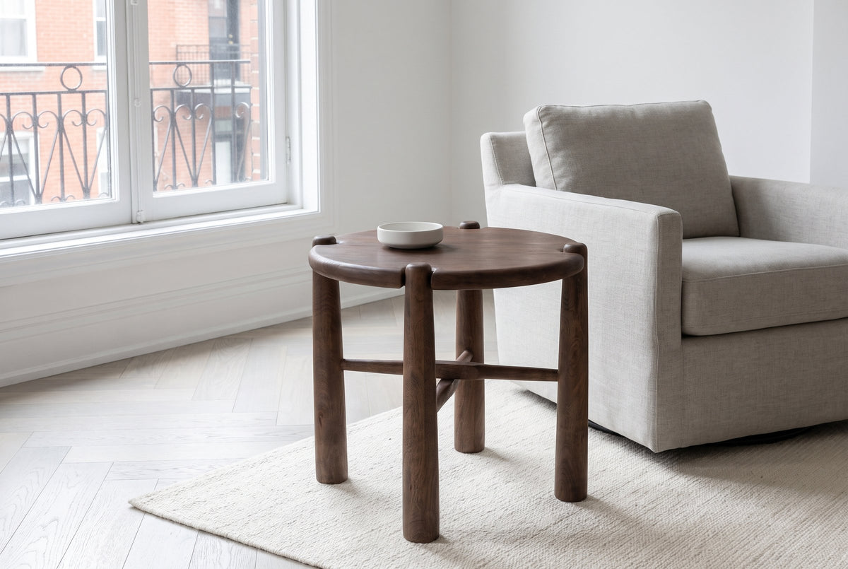 Bettona side table in dark walnut beside a stone-grey linen armchair in a Montreal apartment living room