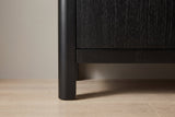 Close-up of a rounded black solid pine corner post becoming a short leg under the bottom rail