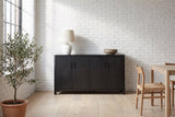 Bibbiena sideboard in black against a white brick wall in a loft dining area, a ceramic lamp and a stoneware bowl on top