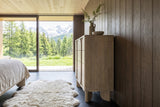 Side view of the Bienno chest in Sand Wash in a Courchevel chalet bedroom, against smoked-oak boards