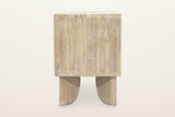 Side view of the Bienno nightstand in Sand Wash on a warm white studio backdrop: a plain finger-jointed side panel over two f