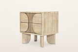 Bienno nightstand in Sand Wash acacia, three-quarter view on a warm white studio backdrop: two drawers with half-round panels